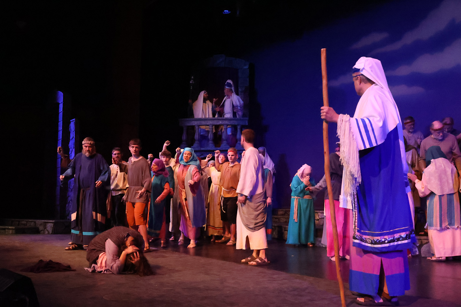 A woman kneels on the floor as Jesus stands near.